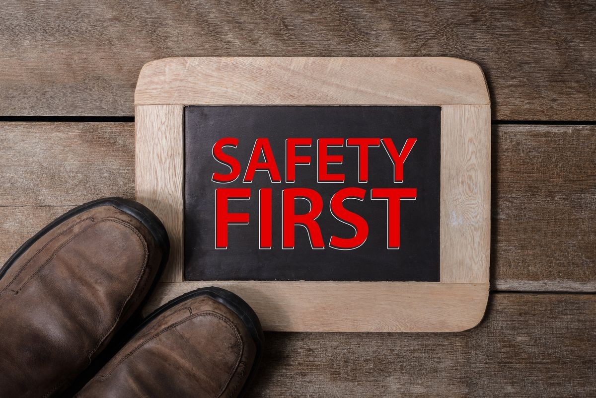 Safety shoes with chalkboard on old wooden background. safety first concepts